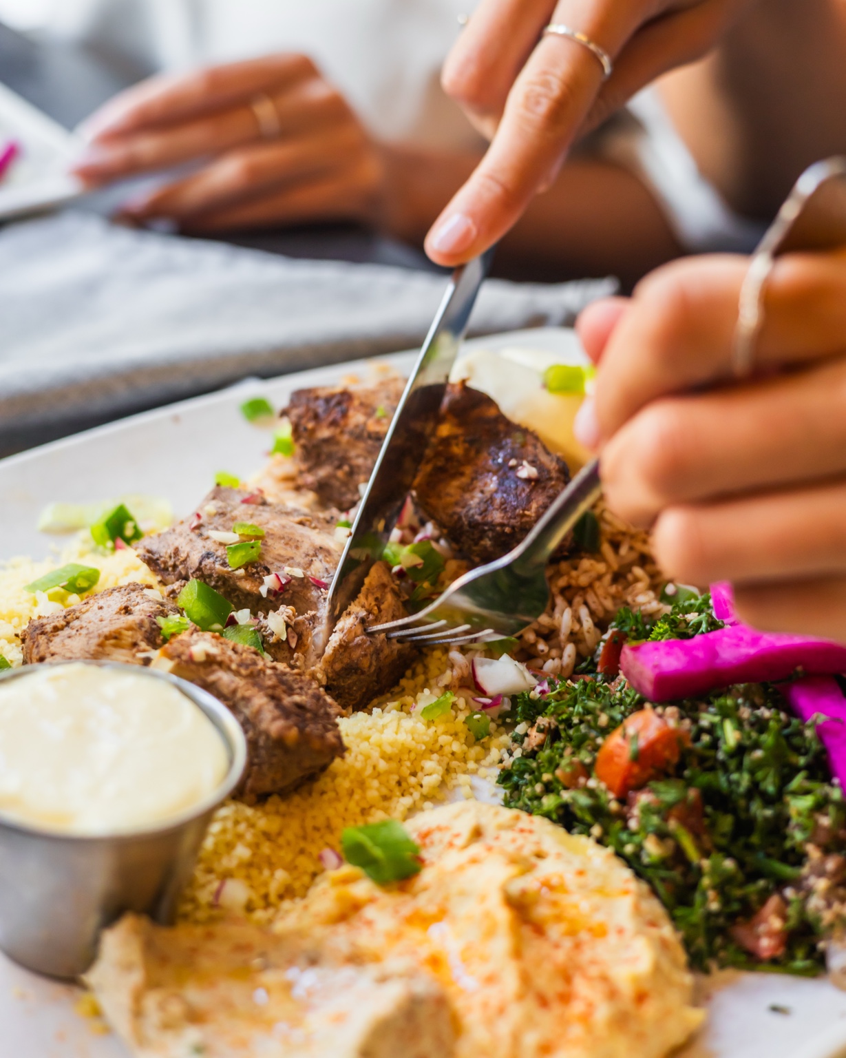 Une personne coupe son repas libanais à table